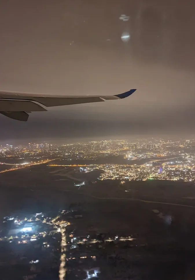 City illuminated beneath airplane wing at night