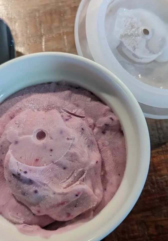 Spoon beside bowl of berry ice cream
